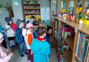 Pani bibliotekarka prezentuje dzieciom książki z działu dziecięcego.